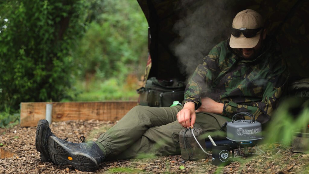 Angler sat on lakeside making cup of tea